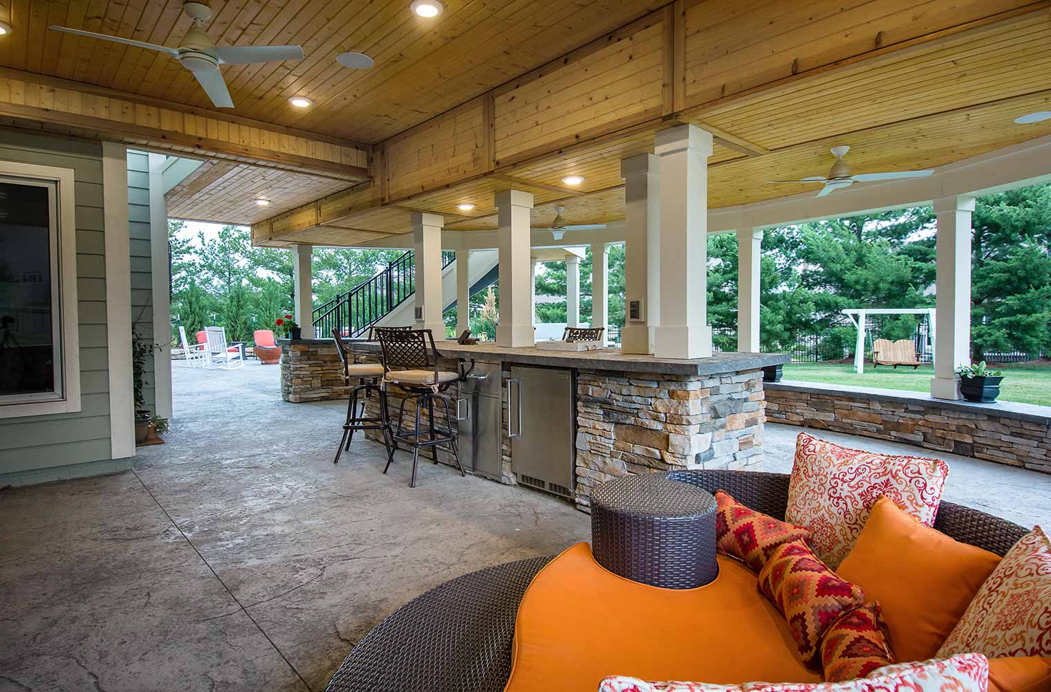 Backyard renovation_An Urbandale lower level patio under the curved deck features a bar and protected TV, designed and built by remodeler and new home builder Silent Rivers of Des Moines, Iowa