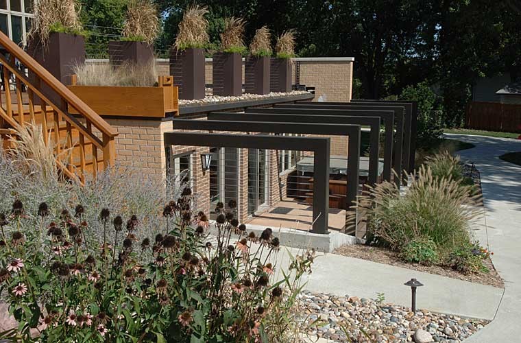 Contemporary steel arbor is softened by tall grasses and landscaping.