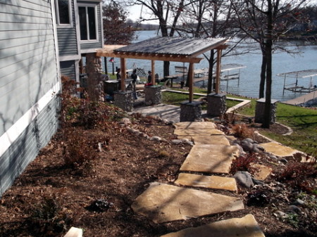 Iowa buff limestone steps lead around the house to this backyard lake patio.
