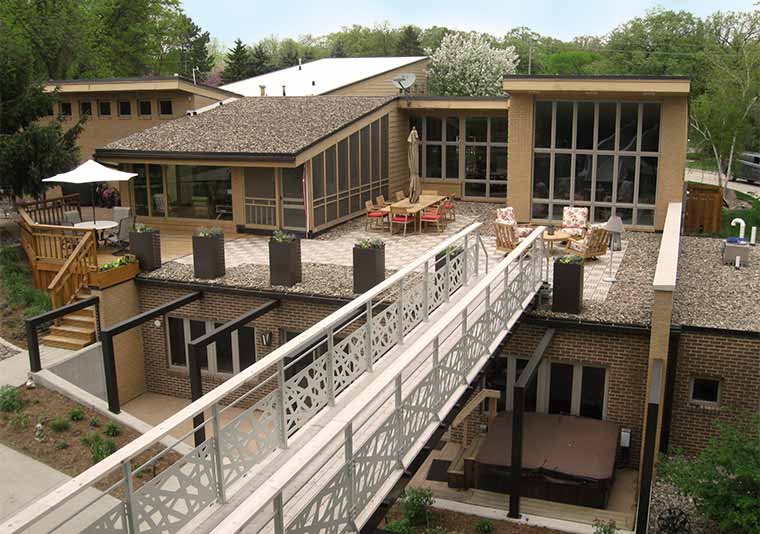 Johnston, Iowa midcentury modern home remodeled by Silent Rivers, view of back deck, walkway bridge, addition