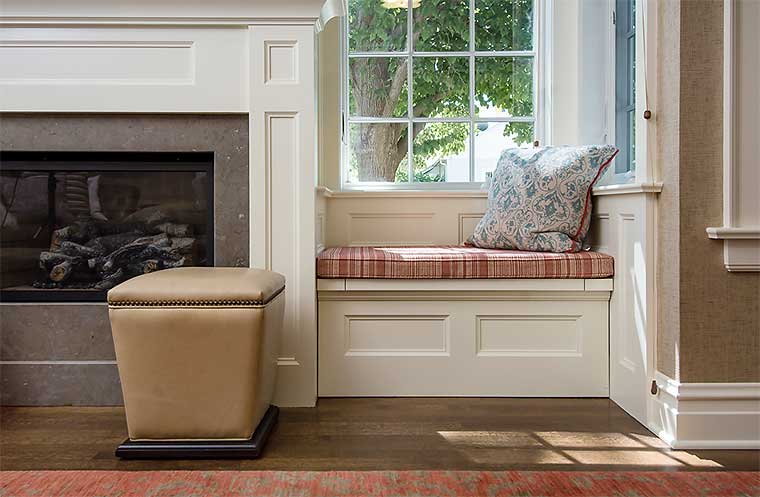 Window seat bench next to fireplace in a sunroom addition designed by Silent Rivers for a 1900s farmhouse
