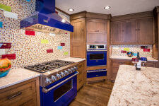 Craftsman kitchen remodel in Adel, Iowa features custom cabinets created by Silent Rivers in quartersawn white oak. The homeowner chose a colorful tile backsplash to complement her art glass collection.