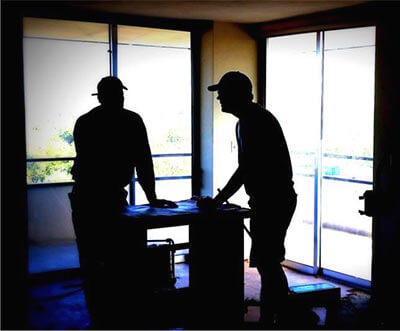 Silhouette of two Silent Rivers carpenters happily working at a job site inside a client's home