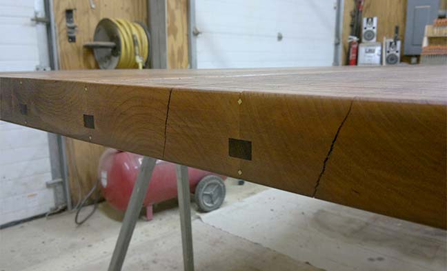 Edge detail of custom designed table for 12 by Silent Rivers has mahogany splines and brass inlays