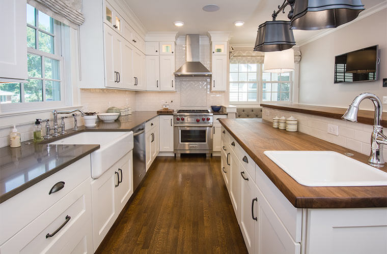 White galley kitchen designed by Silent Rivers for an historic Des Moines colonial farmhouse features walnut butcher block counters and farmhouse sink