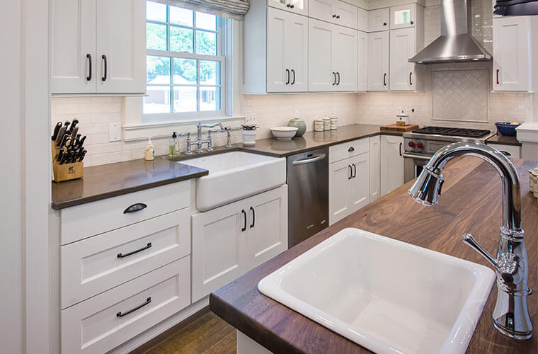 White galley kitchen designed by Silent Rivers in an historic Des Moines colonial farmhouse features butcher block counters and farmhouse sink