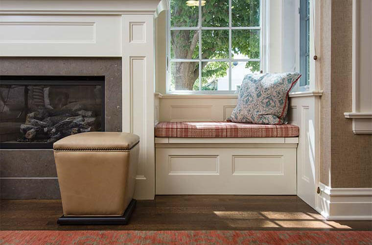 An addition by Silent Rivers on a historic colonial farmhouse contains a sunroom with a cozy fireplace and built-in benches with storage.