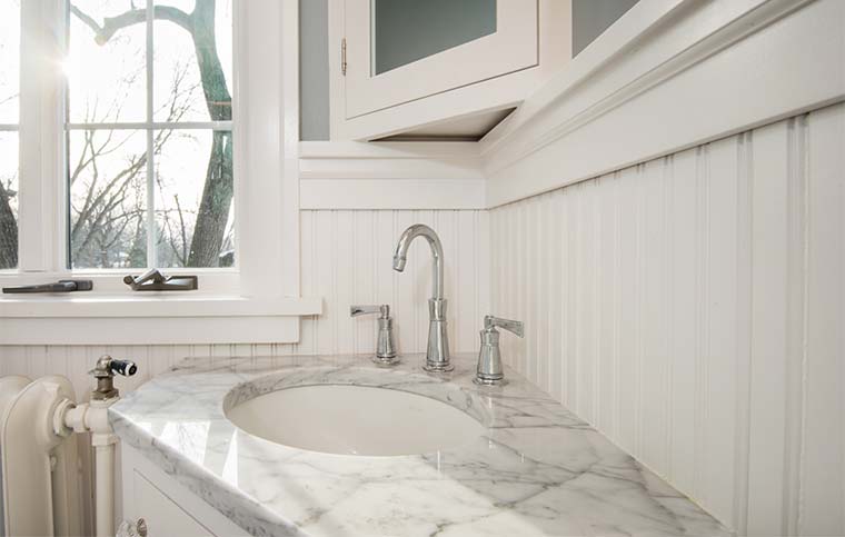 Corner vanity with white marble countertop, wide spread faucet in 1920 craftsman bathroom remodel in Des Moines by Silent Rivers
