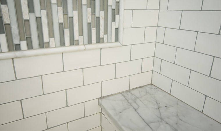 Shower tile, inset glass tile and marble top bench in a Des Moines 1920 craftsman bathroom remodel by Silent Rivers