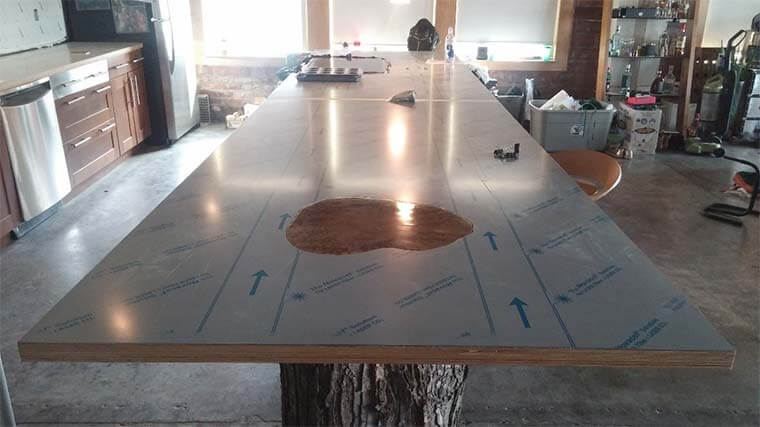 Installation of a 16 foot stainless steel countertop supported by a maple tree stump in a downtown Des Moines loft remodel by Silent Rivers