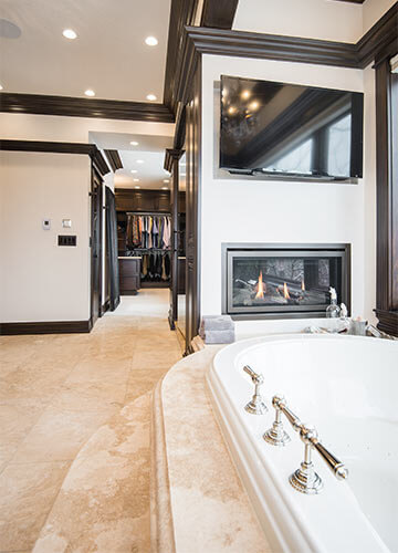 Urbandale-Iowa-luxurious-traditional-master-bathroom-by-Silent-Rivers with fireplace and travertine deck around soaking tub