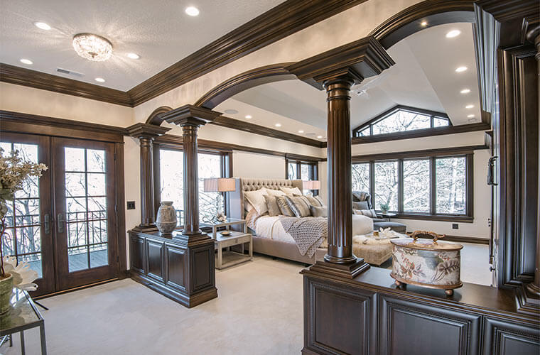 Urbandale-Iowa-luxurious-traditional-master-bedroom-by-Silent-Rivers with colonnade arches and ornate chocolate stained woodwork