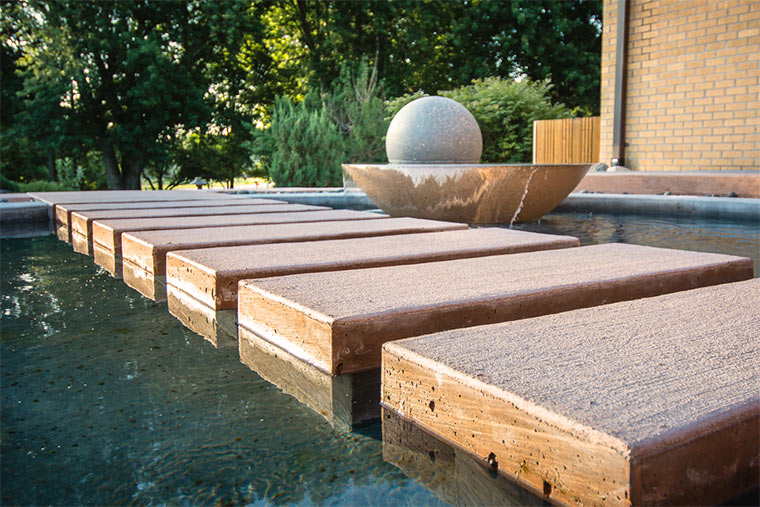 Reflecting pool with water fountain and floating stepping stones in Johnston, Iowa home landscaped by Silent Rivers