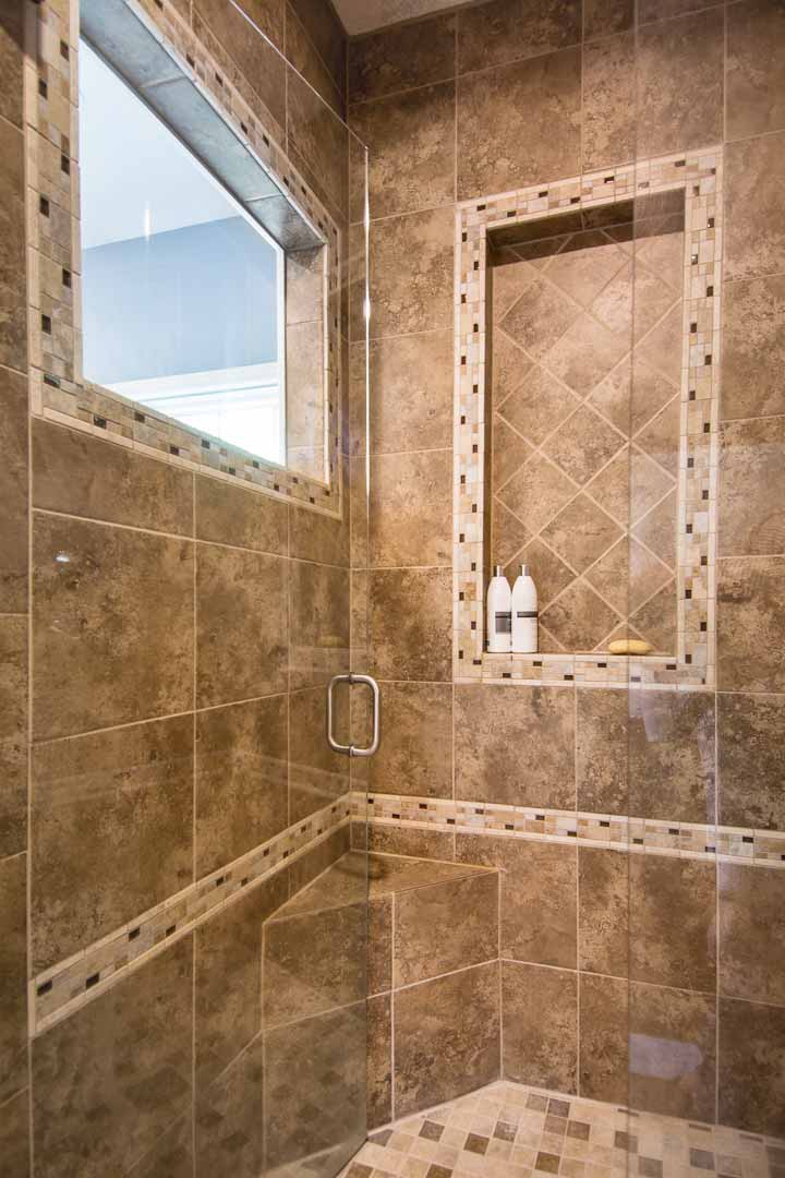 Tiled shower with inset shelf, corner bench and window to let in natural light in master bathroom remodel by Silent Rivers Des Moines