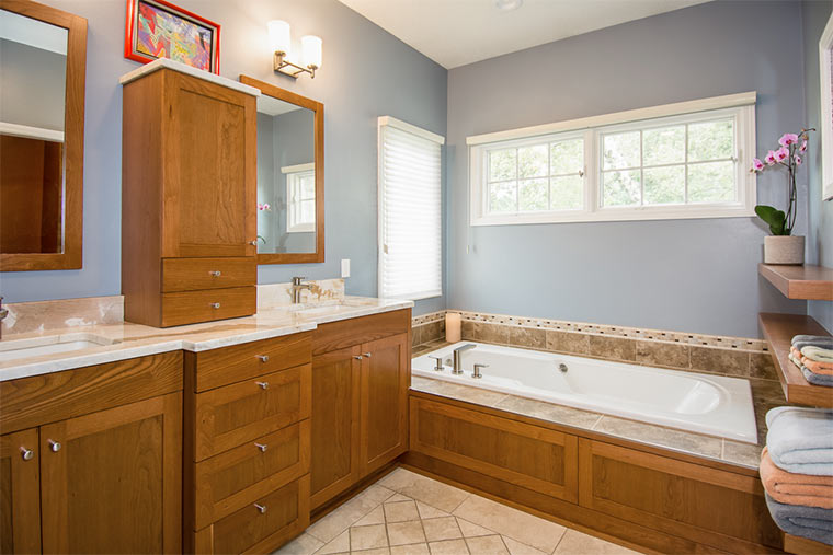 Master bathroom remodel by Silent Rivers Des Moines features custom cherry cabinets, tile tub surround and brushed nickel faucets