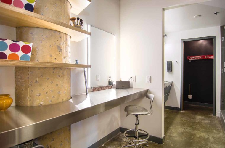 Exposed concrete column in bathroom of downtown Des Moines loft remodeled by Silent Rivers features birch plywood shelves contoured around column