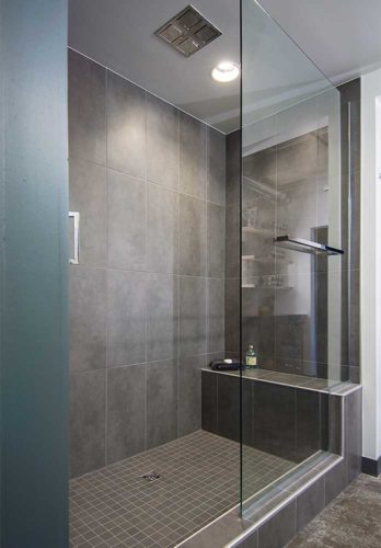 Oversized gray tile stacked vertically in bathroom remodel of downtown Des Moines by Silent Rivers