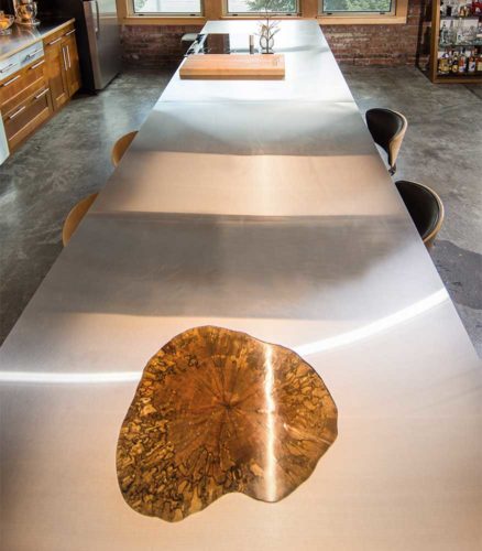 16 foot long stainless steel kitchen island with integrated cross section of maple tree in downtown Des Moines, Iowa loft remodeled by Silent Rivers
