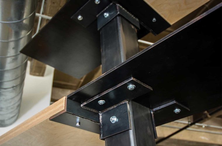 Welded steel brackets and posts support birch shelves on custom entertainment center room divider in downtown Des Moines loft remodel by Silent Rivers