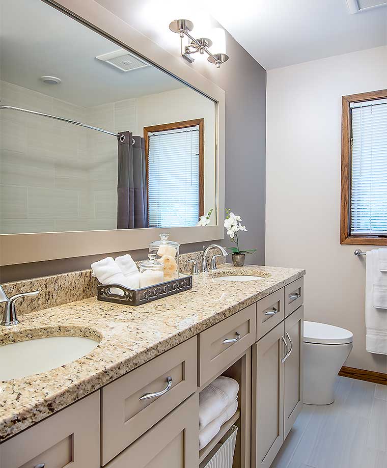 Bathroom remodel by Silent Rivers brings contemporary style to a 1980s bathroom with double vanity, granite counter, modern lighting and beautiful tile to this Des Moines, Iowa home
