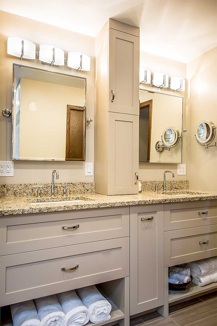 Tilted mirrors over a double vanity with contemporary bathroom lighting and custom cabinetry by Silent Rivers, Des Moines, Iowa
