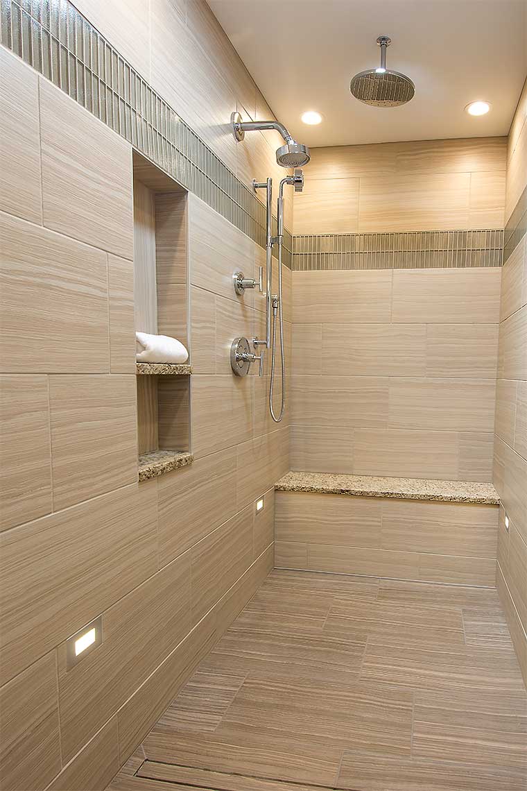 Zero entry shower with linear floor drain and linear tile features built in shelving and bench in a 1980s bathroom remodel by Silent Rivers, Des Moines, Iowa