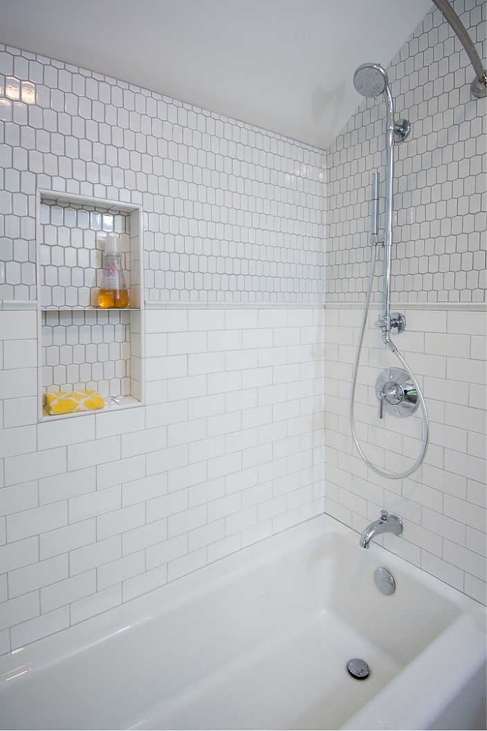 White subway tile and hexagon tile in shower with cast iron tub and shower column by bathroom remodeler Silent Rivers, Des Moines
