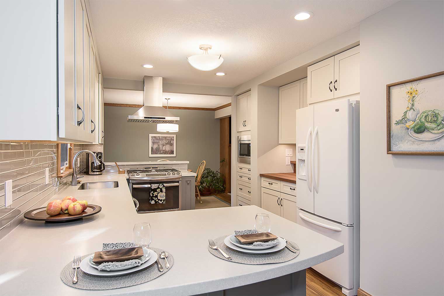 Casual counter dining area in new Des Moines kitchen by remodeler Silent Rivers features white cabinets and counters