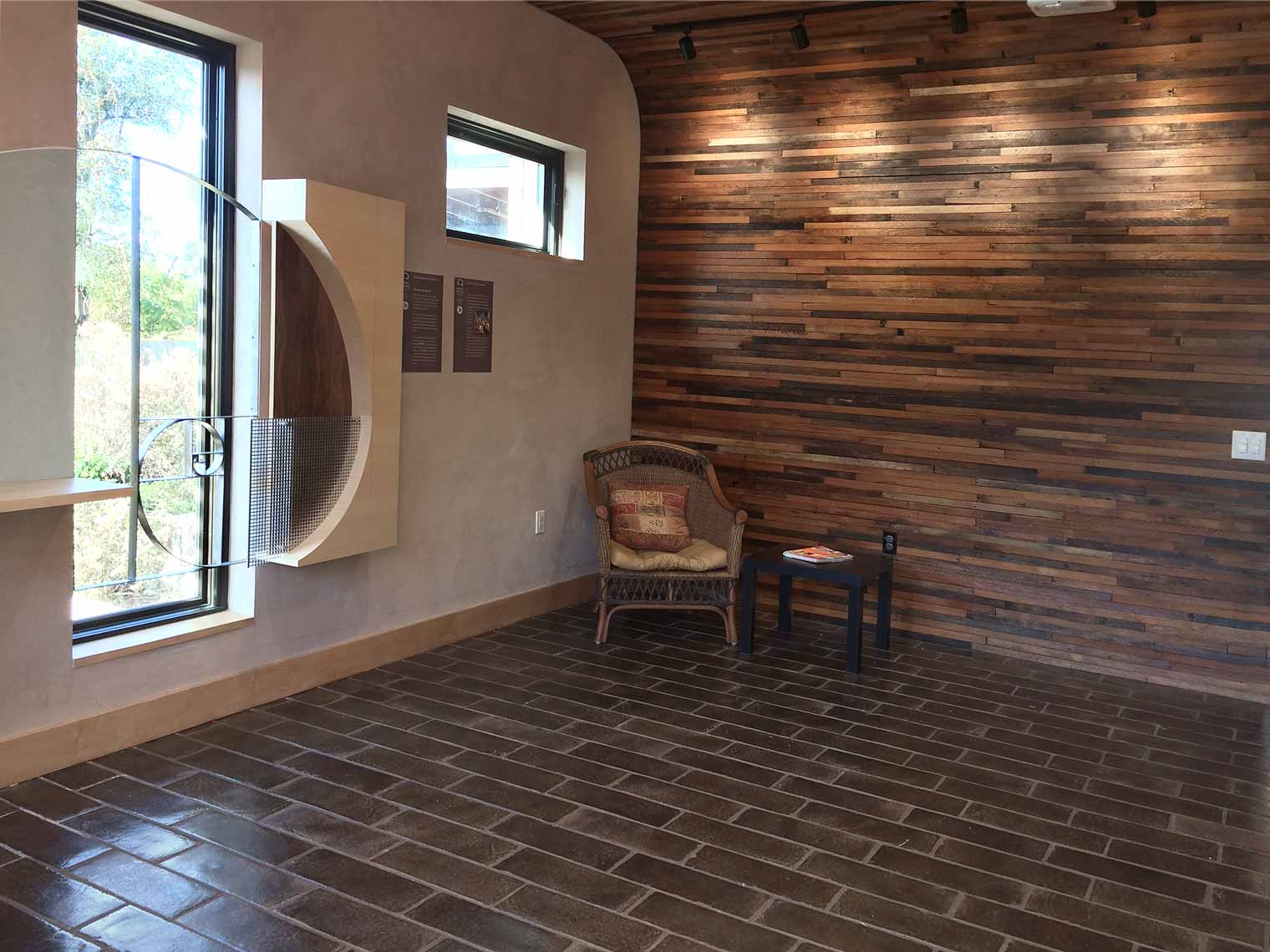 The “Sacred Commons” area at Healing Passages Birth & Wellness Center at the Green & Main building features wooden lathe wall treatment, clay tile, curved wall and ceiling and a spiral art sculpture.