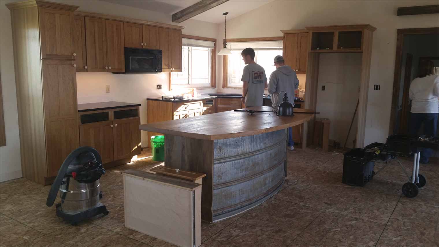 Remodeling of farmland kitchen by Silent Rivers features rustic island is made from old silo parts and the wooden top is repurposed lumber. 