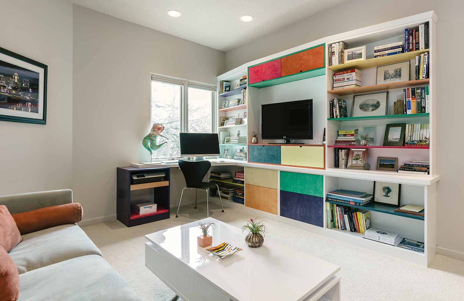 Built-in custom bookshelves, storage, entertainment center and desk create colorful, functional space solutions for a Des Moines condo, Silent Rivers