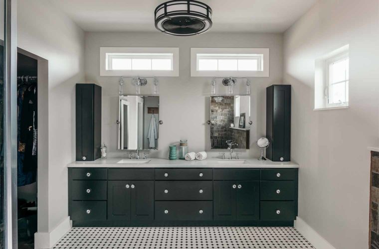 Industrial farmhouse style master bathroom in barn style custom new home in St. Charles, Iowa designed and built by Silent Rivers of Des Moines features onyx Wellborn cabinets, white countertops and industrial light and ceiling fan fixture