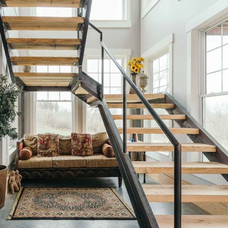 industrial farmhouse style custom new home in St. Charles, Iowa designed and built by Silent Rivers features a grand staircase made of steel channel and bridge plank lumber