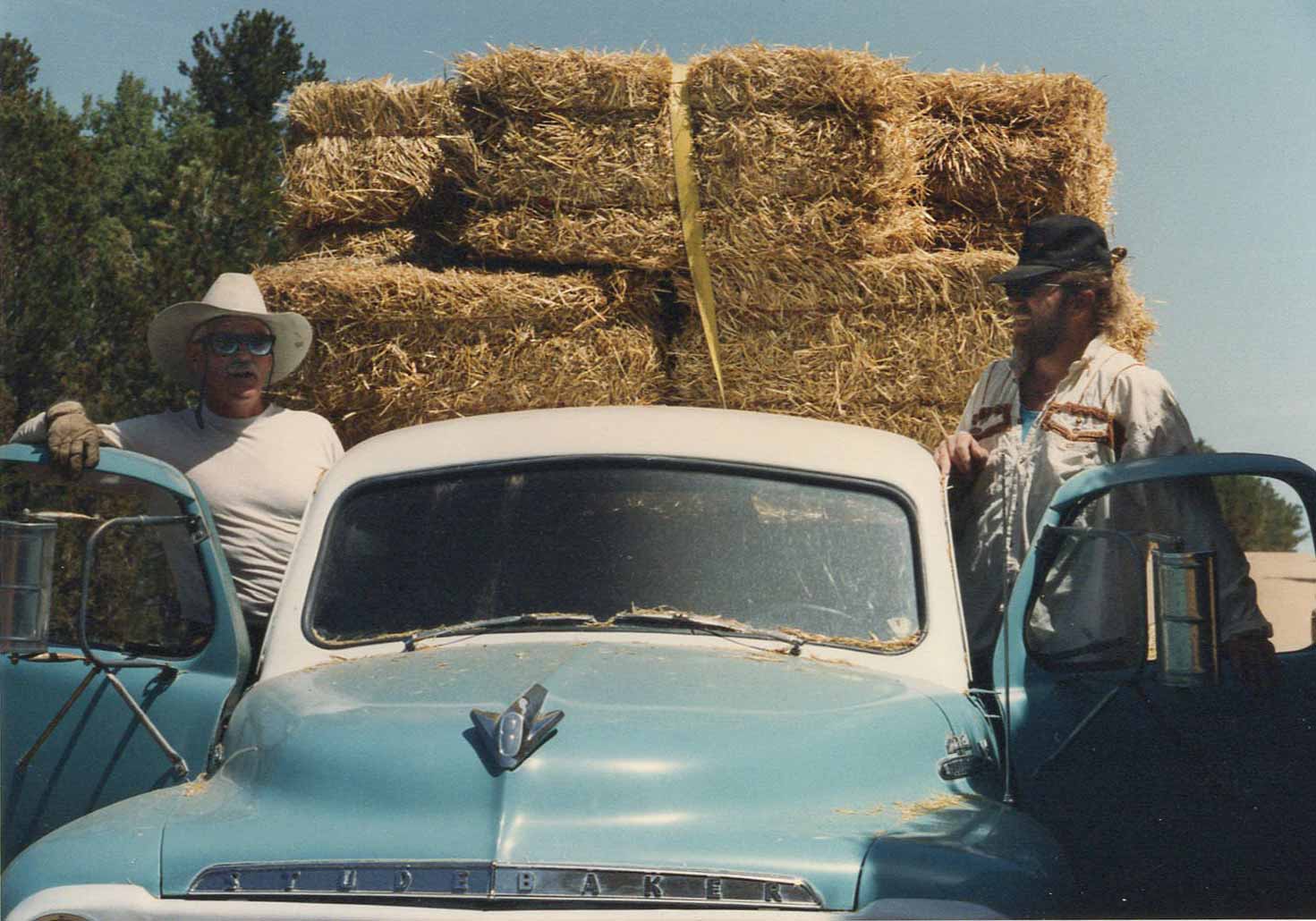 Two men deliver straw bales in an old Studebaker truck to the house Molly Spain helped build in New Mexico for her mom