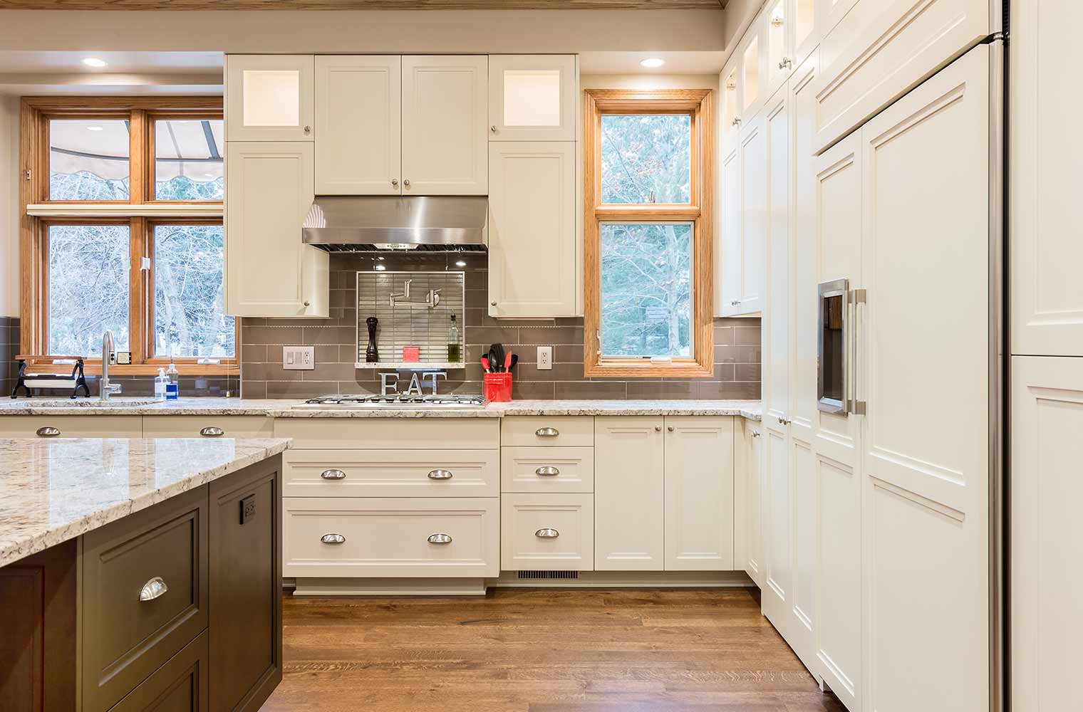 Large kitchen remodel in Clive, Iowa designed and built by Silent Rivers features custom white cabinets, large dark center island, upper display cabinets