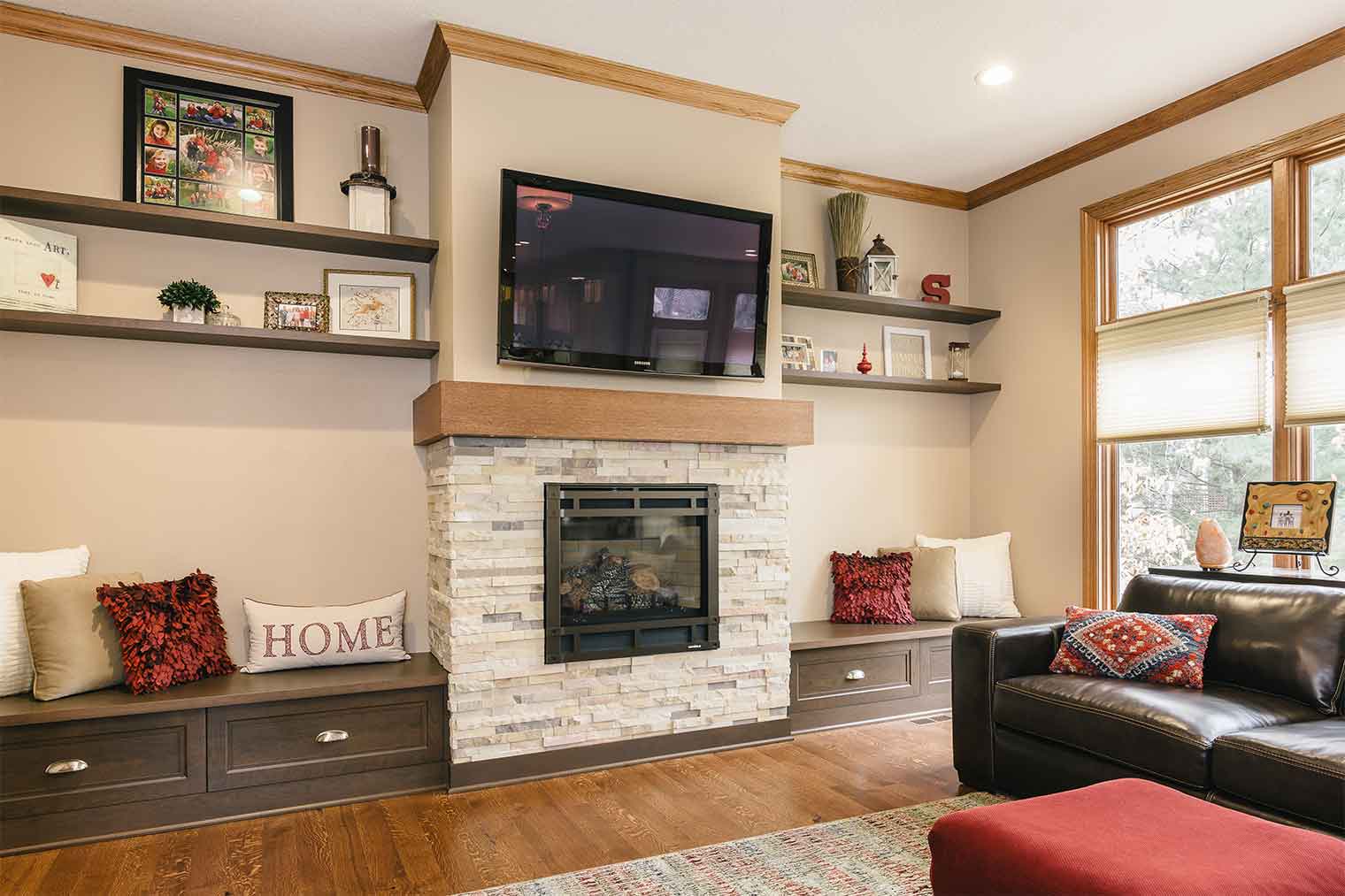 Family room remodel off of large kitchen remodel designed and built by Silent Rivers of Clive, Iowa features stone fireplace, bench seats and wrap around mantel