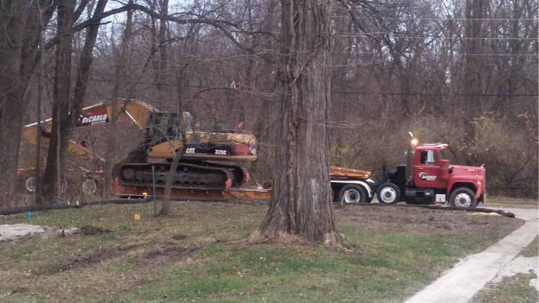 Excavator and demolition crew arrives to remove existing home where a new custom home will be built by Silent Rivers on this Des Moines, Iowa lot