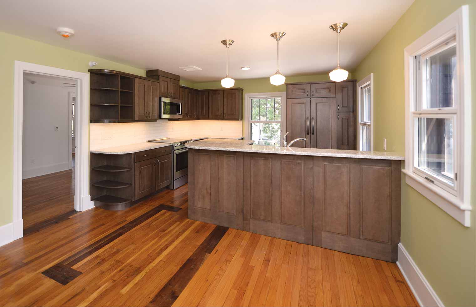 kitchen in residential space of Green & Main building above Healing Passages Birth & Wellness Center in Des Moines was designed and historically renovated by Silent Rivers featuring salvaged wood floors, Wellborn cabinetry, Cambria countertops and Bosch stainless steel appliances