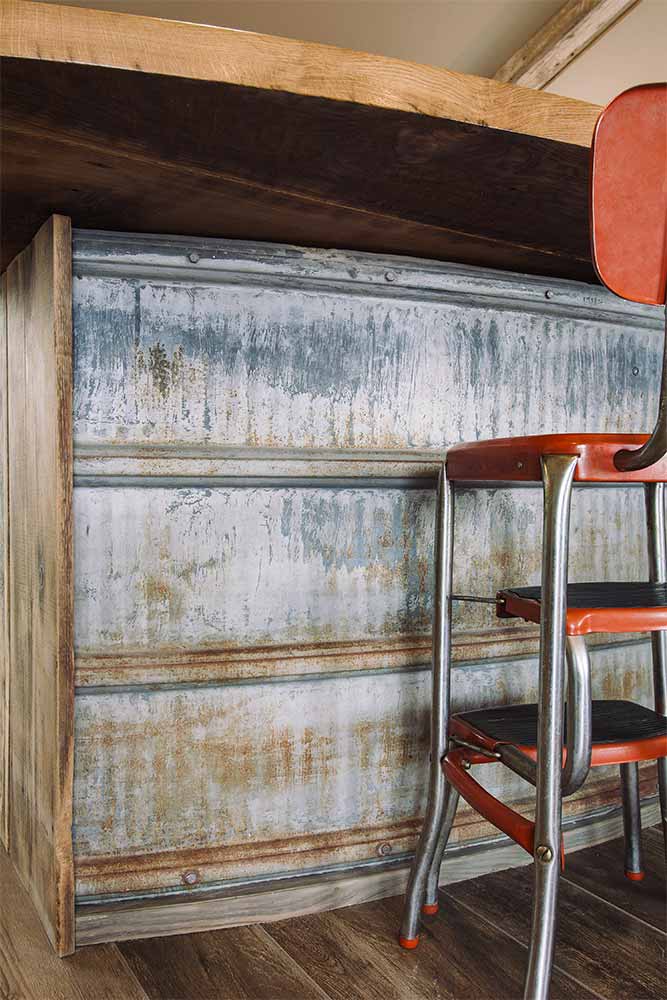 weathered metal silo siding on curved bar front rustic kitchen island designed by Silent Rivers for a rural Iowa retreat