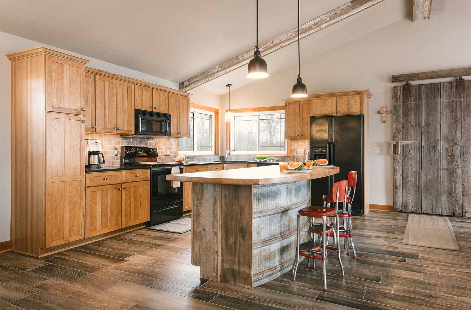 Rustic kitchen with curved island designed with recycled and upcycled metal and barn wood in central Iowa designed and built by Silent Rivers for a rural Iowa retreat