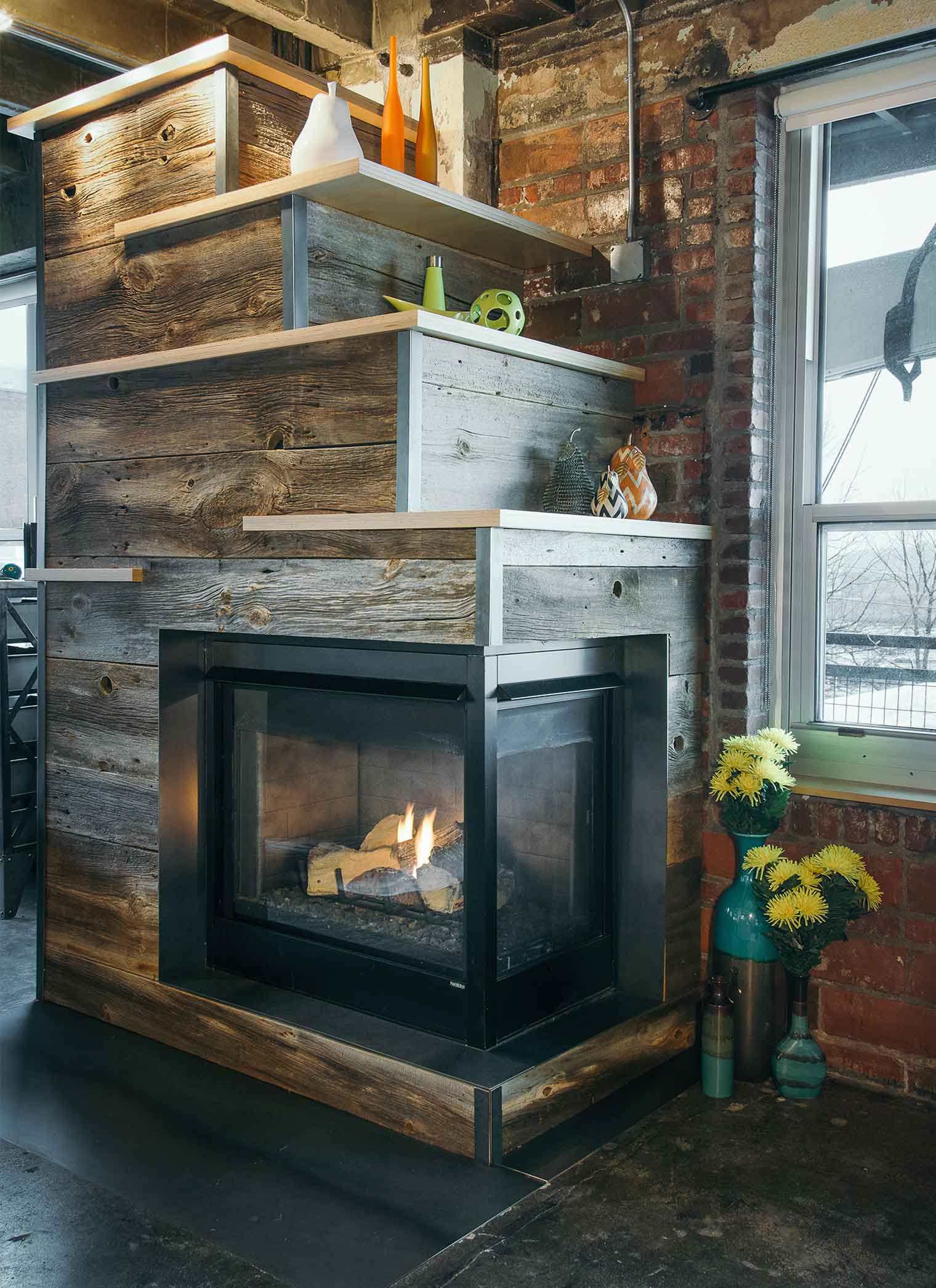 Baltic birch shelving in unique design on salvage barn wood fireplace in downtown Des Moines loft designed by Silent Rivers Design+Build