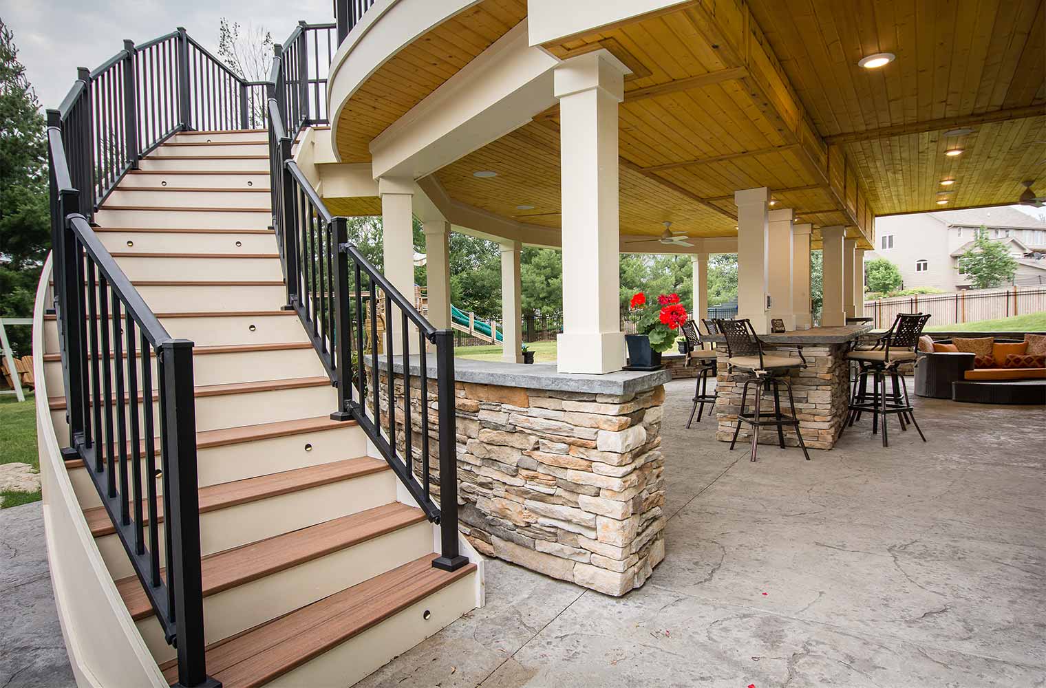 Backyard renovation_Curved and staircase on an Urbandale patio, curved deck and spa features a bar and protected TV, designed and built by remodeler and new home builder Silent Rivers of Des Moines, Iowa