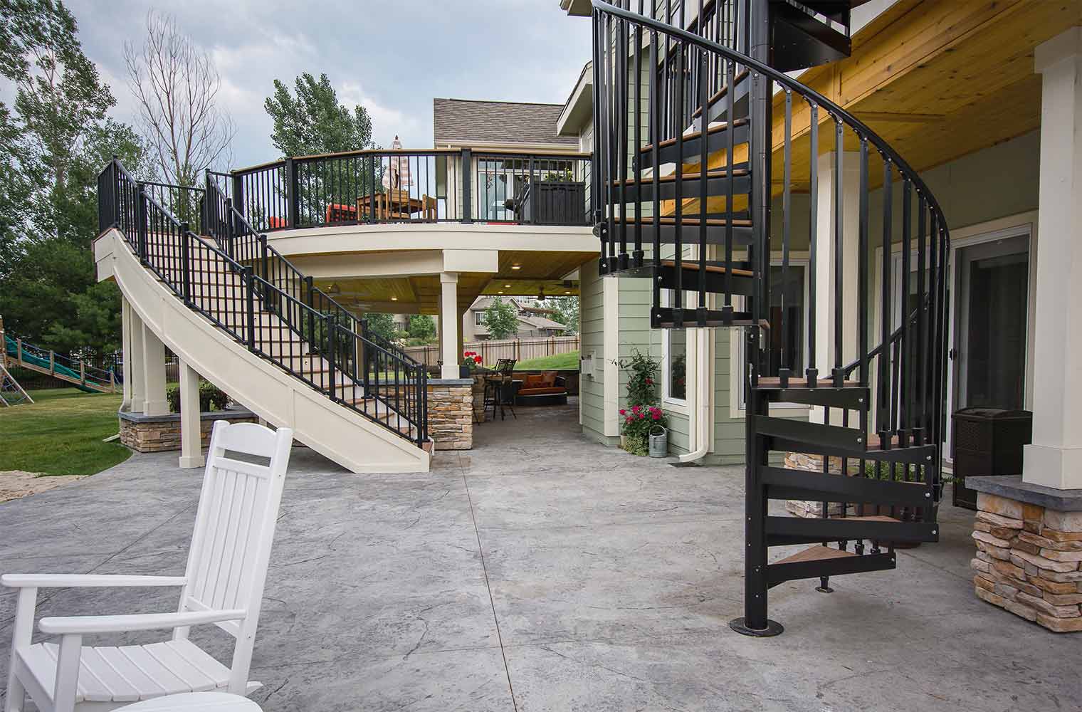 Backyard renovation_Curved and spiral staircases flank an Urbandale patio, curved deck and spa features a bar and protected TV, designed and built by remodeler and new home builder Silent Rivers of Des Moines, Iowa