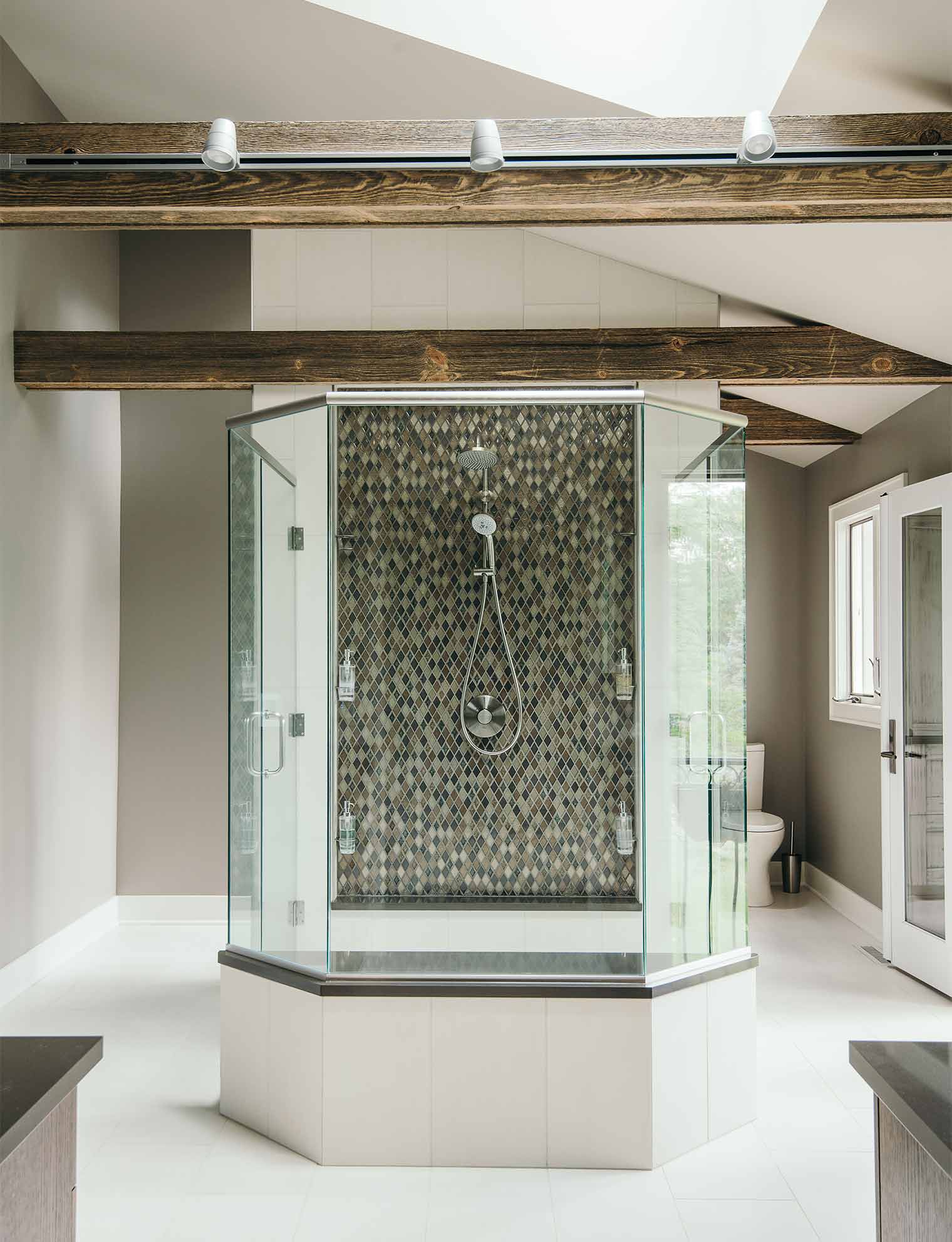 glass enclosed shower in center of master bathroom with two doors on each side, bench and diamond shaped tile by designer and remodeler Silent Rivers of Des Moines, Iowa