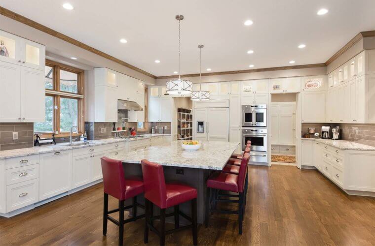 large transitional kitchen in Clive, Iowa features oversized island, lighted upper display cabinets, walk-in pantry designed by remodeler Silent Rivers