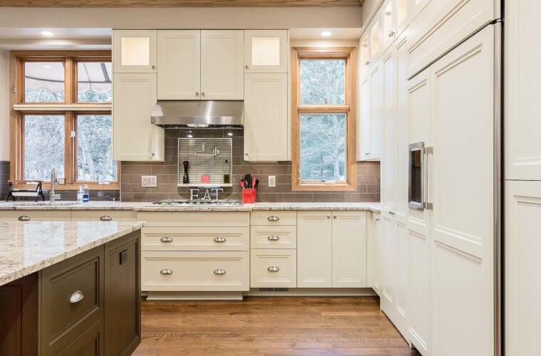 Large kitchen remodel in Clive, Iowa features custom white and dark cabinets and cabinet depth refrigerator with custom panels by remodeler Silent Rivers of Des Moines