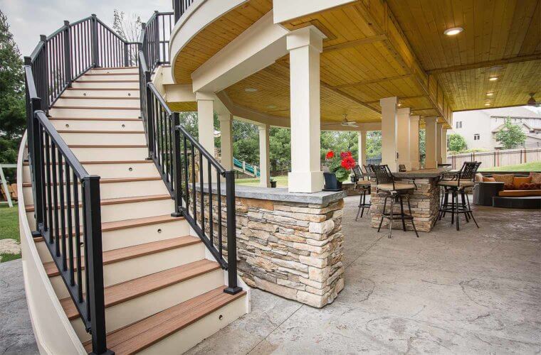 curved staircase leads from covered deck and outdoor bar area to upper curved deck by builder Silent Rivers of Des Moines, Iowa