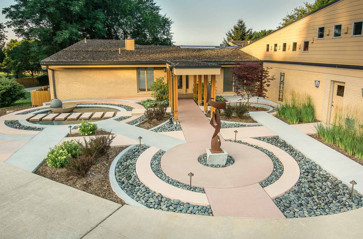 contemporary front entry courtyard with concentric circles, metal sculpture, spherical water fountain with floating stepping stones in Johnston, Iowa by Silent Rivers