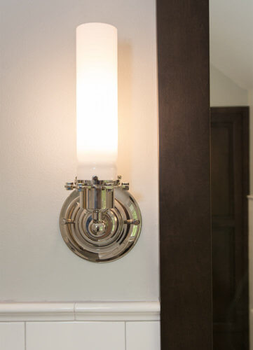 chrome and frosted glass wall sconces beside mirror in Des Moines bathroom by remodeler Silent Rivers