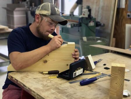 Alex Schlepphorst woodworker artisan hand carves wood corbel in Silent Rivers woodshop